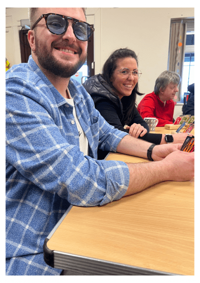 Motability Operations corporate volunteers joyfully playing uno with Paul's Place members